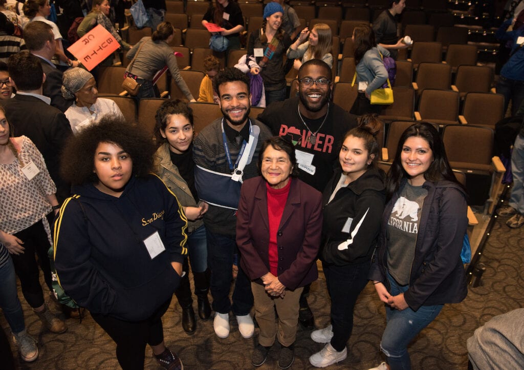 Dolores Huerta standing beside students.